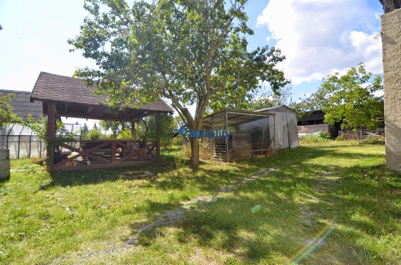 A garden at a family house in Badín with a gazebo and wooden shelters.