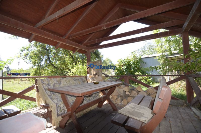 Covered terrace at a family house in Badín with wooden seating and garden vegetation.
