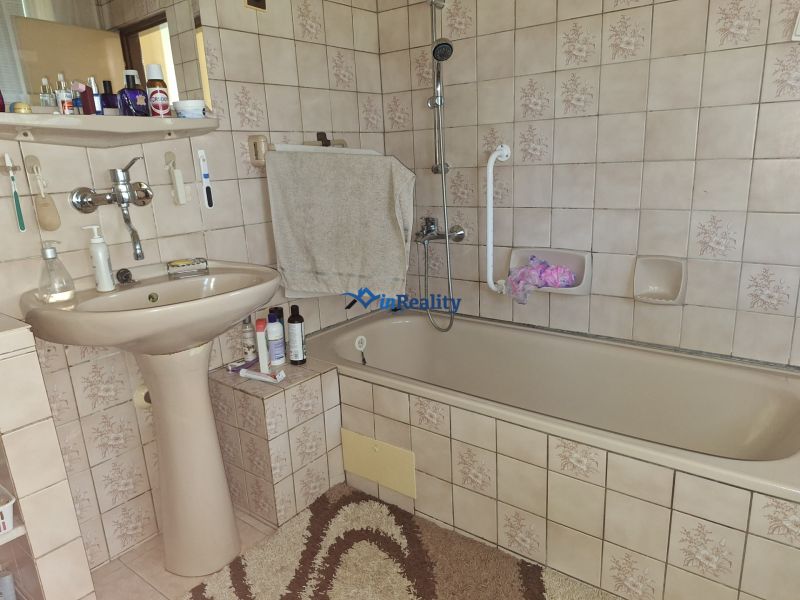 A bathroom in a family house with a sink, a bathtub, and ceramic tiles.