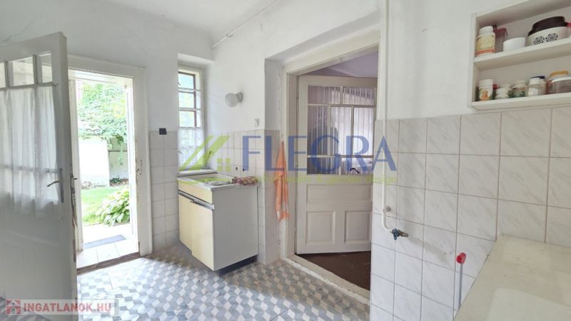 A kitchen in a family house with white walls and a tiled floor.