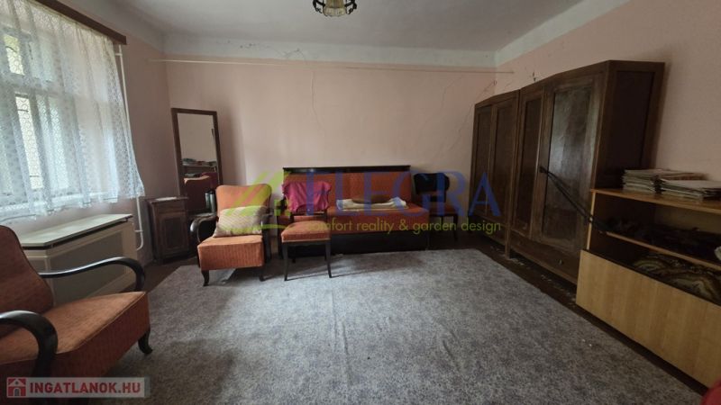A living room in a family house with carpet flooring and wooden furniture.