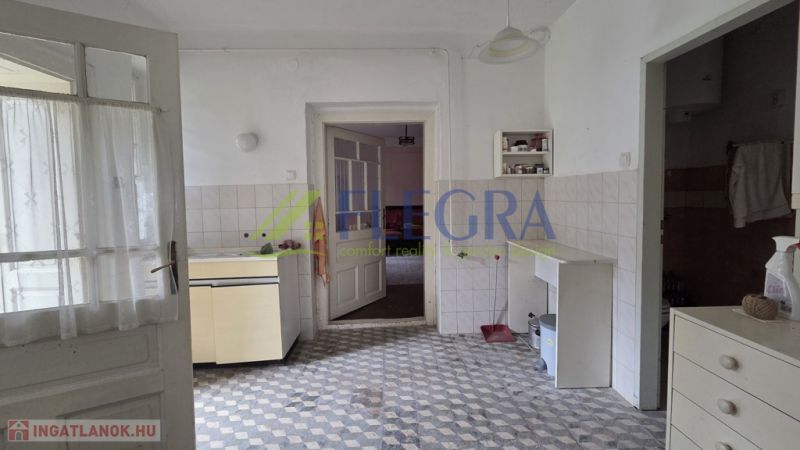 A kitchen in a family house with a tiled floor and simple furnishings.