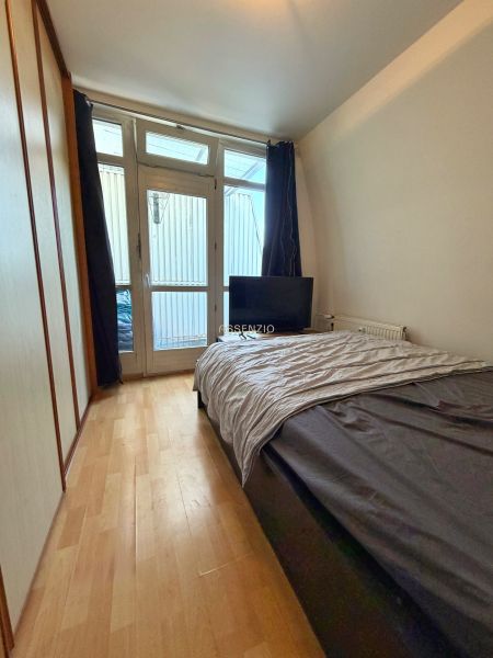 Bedroom in a 2-room apartment with a bed, wardrobe, and floor with wooden decor.