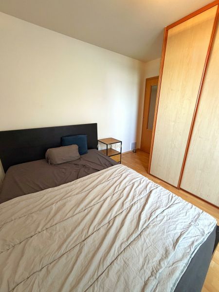 Bedroom in a 2-room apartment with a bed, cabinet, and floor with wood decor.