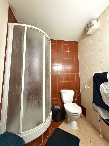 A bathroom in a 2-room apartment with a corner shower and simple sanitary facilities.