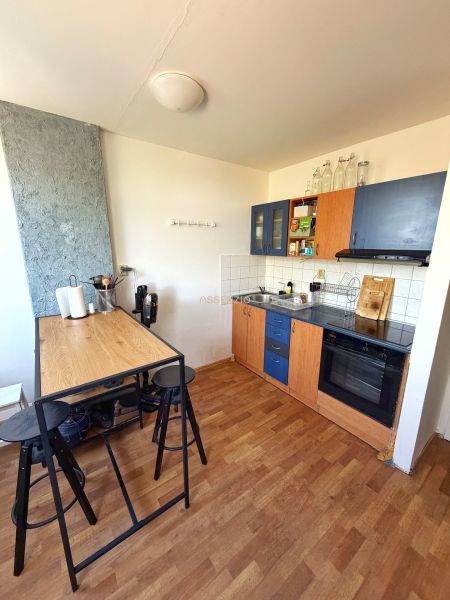 A kitchen in a 2-room apartment with a counter and a wooden decor floor.