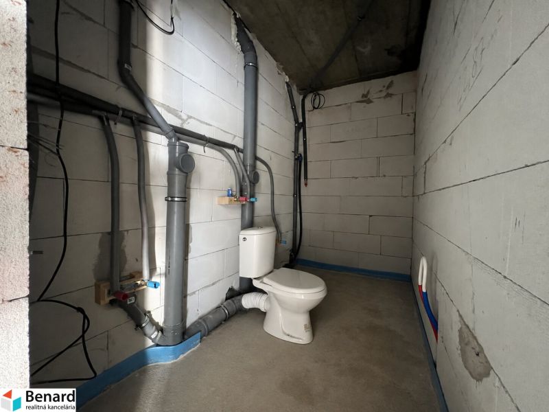 Unfinished commercial space with sanitary facilities, concrete walls, and floor.