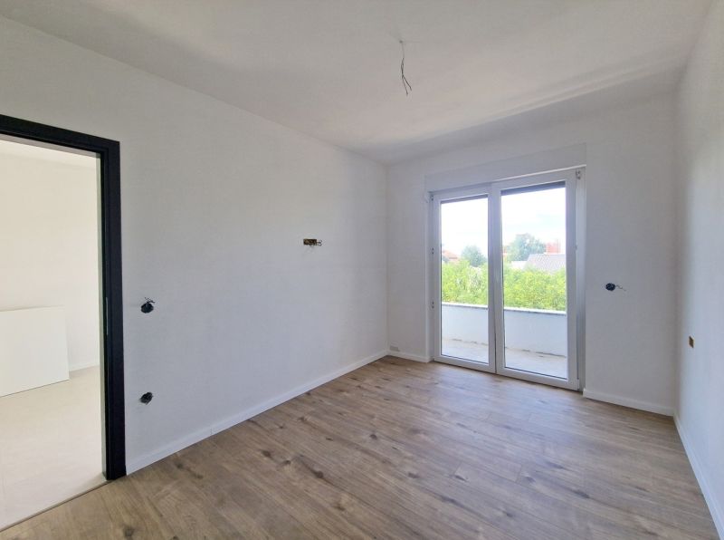 A room in a 3-room apartment with a wooden decor floor and large windows.