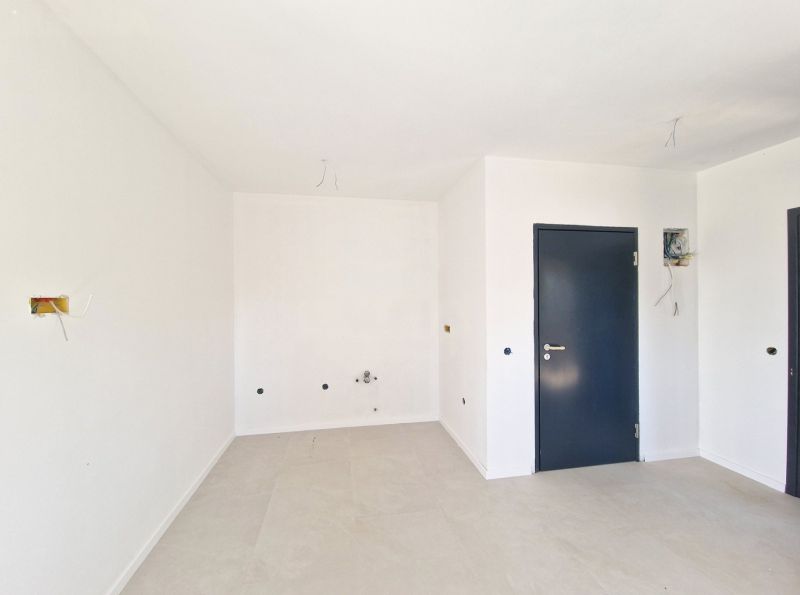 Empty room with neutral flooring and a door in a three-room apartment.
