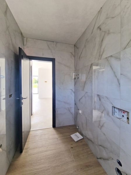 A bathroom with marble walls and a wooden decor floor in a 3-room apartment.