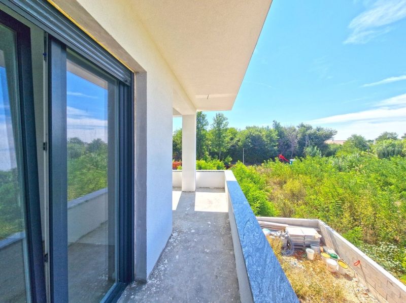 A balcony of a 3-room apartment in Privlaka with a view of greenery and blue sky.