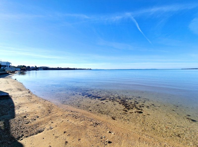 Sandy beach with clear water in Privlaka, ideal for relaxing by the sea.
