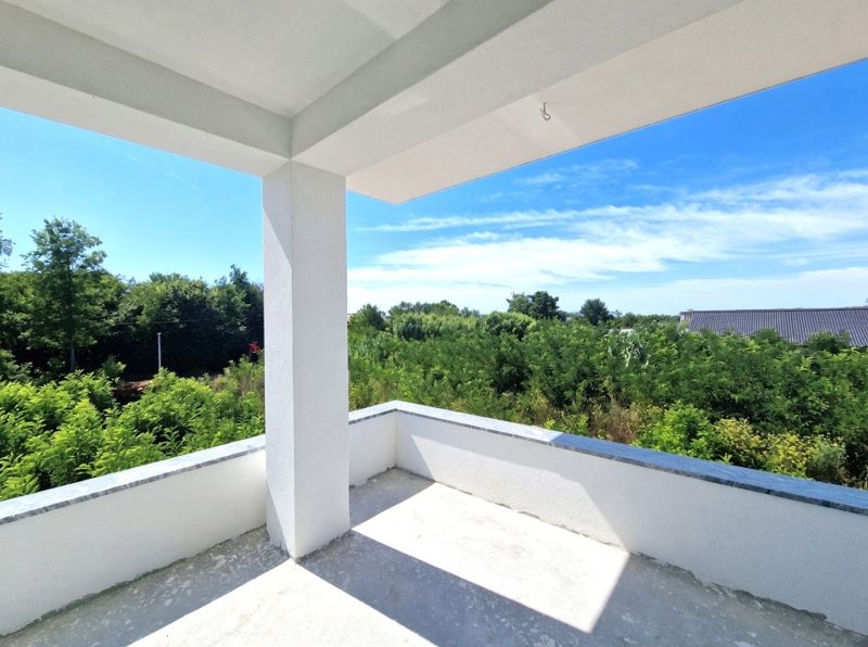 The balcony of a 3-room apartment in Privlaka with a view of greenery and a blue sky.