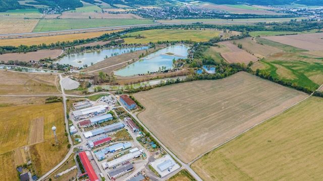 Aerial view of warehouses and halls in Dulov surrounded by fields and water bodies.