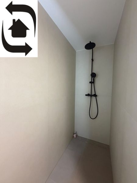 Shower corner with a black shower in a 2-room apartment, light walls, minimalist design.