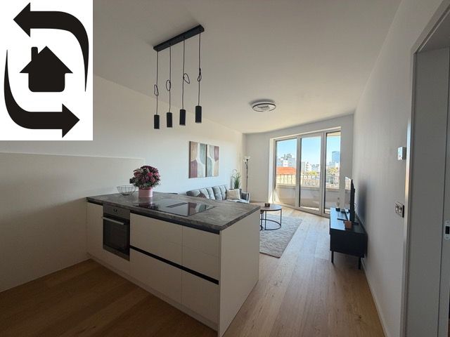 A kitchenette in a 2-room apartment with a wooden decor floor and a view of the city.