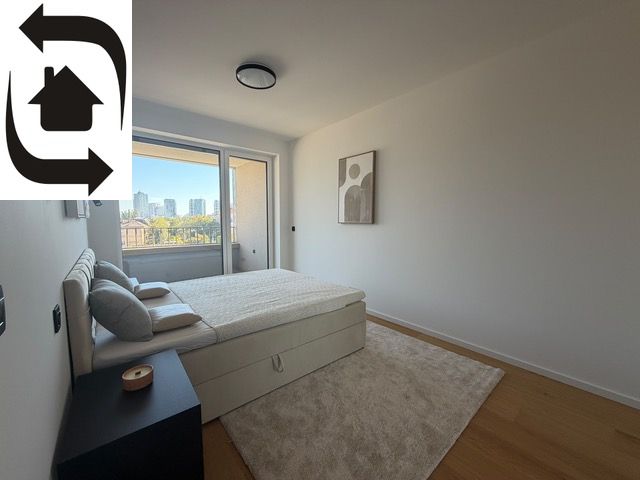 Simple bedroom with a large bed, a painting, and a view. Floor with wooden decor.