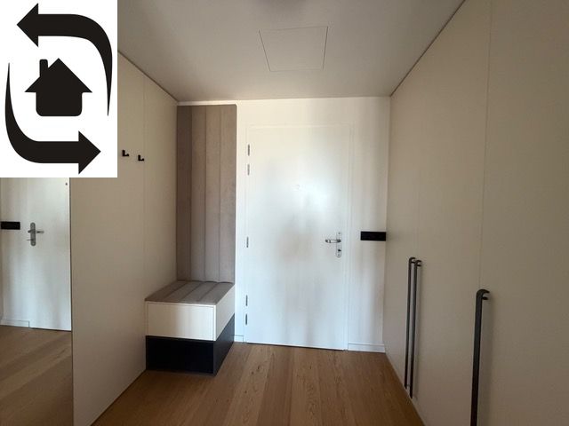 Entrance hallway with white doors and a wooden decor floor in a 2-room apartment.