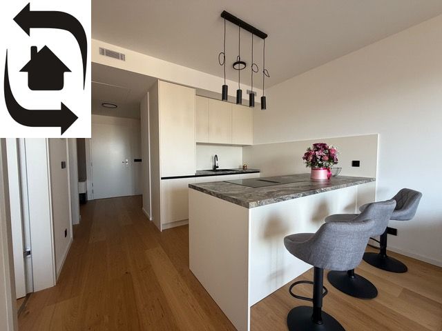 A kitchen in a 2-room apartment with a central island and a wooden-patterned floor.