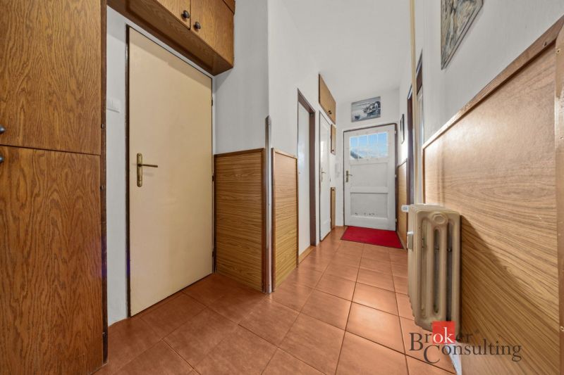 A hallway in a 3-room apartment with ceramic tiles, wooden paneling, and built-in cabinets.