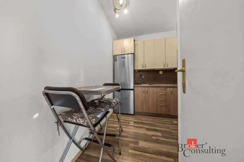 A kitchen in a 3-room apartment with a kitchen unit, appliances, and a floor with a wood decor.