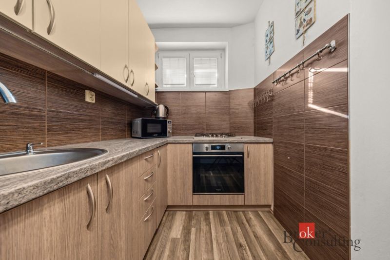 A kitchen in a 3-room apartment with a wooden decor floor and appliances.