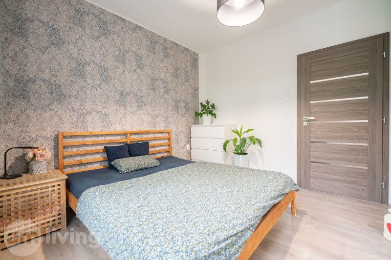 A bedroom in a 3-room apartment with floral wallpaper and a wooden decor floor.