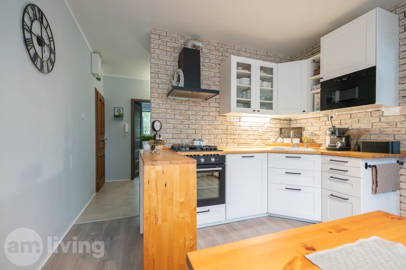 A kitchen with brick cladding and a wooden decor floor in a 3-room apartment.