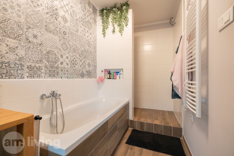 A bathroom in a 3-room apartment with decorative tiles and a wooden-patterned floor.