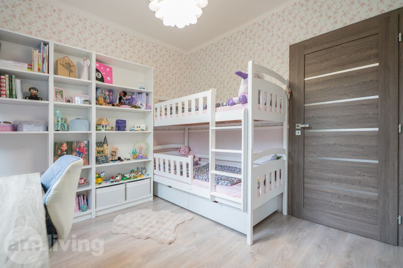 A children's room in a 3-room apartment with a bunk bed and shelves full of toys.