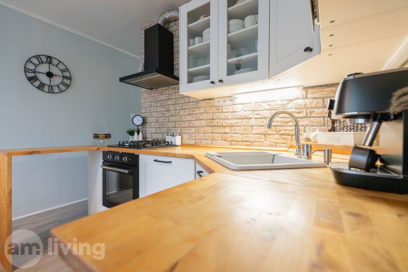 A kitchen in a 3-room apartment with brick cladding and a wooden decor floor.