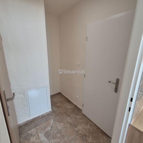 The entrance hall of a studio apartment with ceramic tiles and white walls, a simple interior.