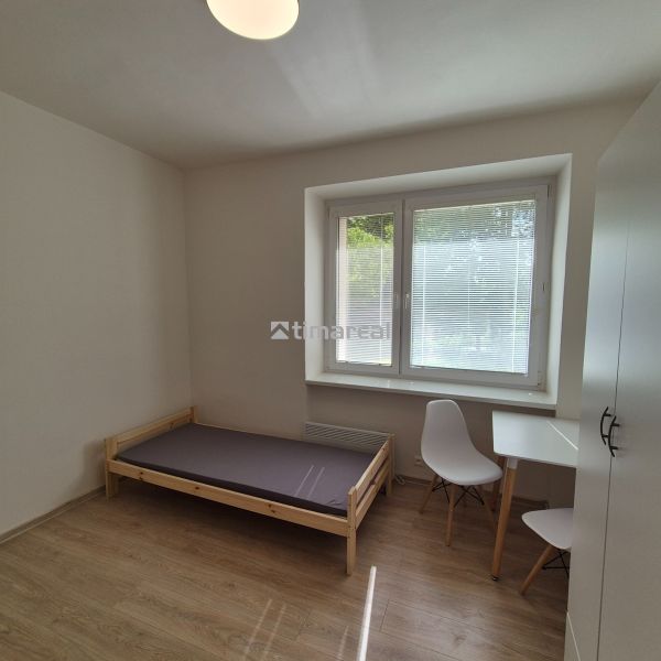 Studio apartment with a bed, table, and wooden floor decor, bright room.