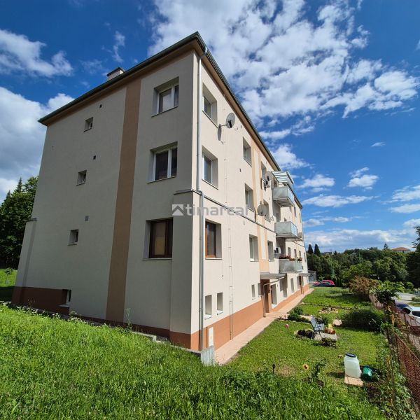 An apartment building on Kpt. Uhra in Myjava, surrounded by greenery and blue skies.