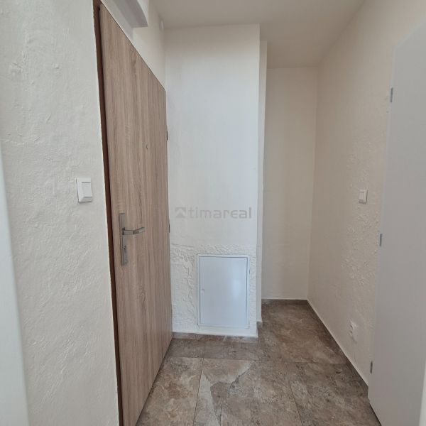 Entrance hall of a studio apartment with ceramic tiles and wooden doors.