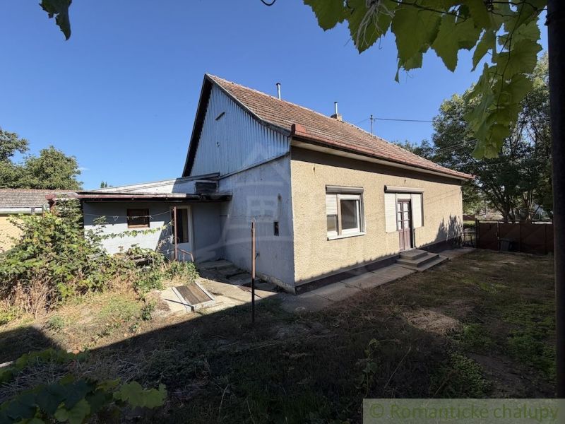 A family house in Tvrdošovce with a traditional roof and a garden surrounded by greenery.