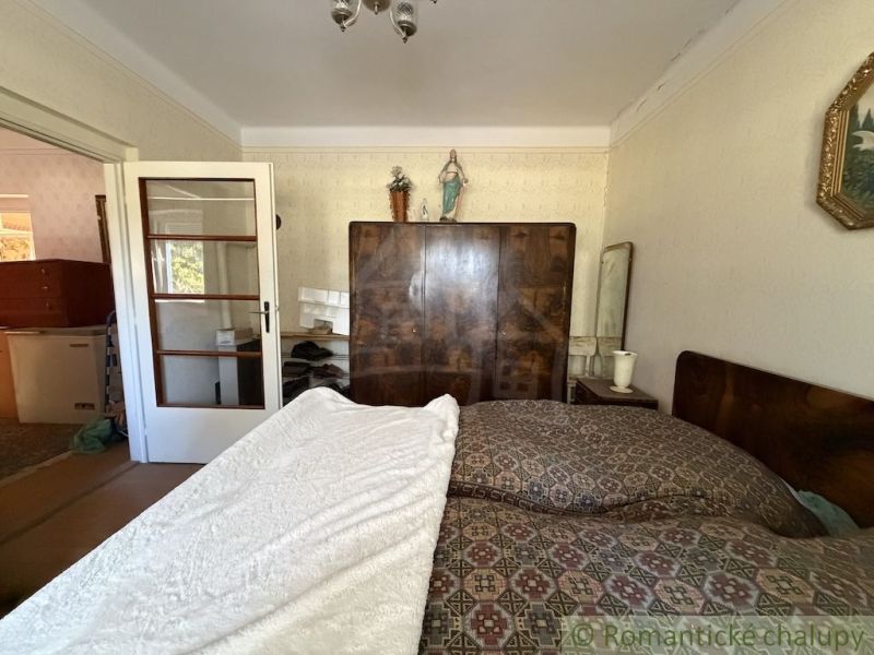 A bedroom in a family house with a large bed, a wardrobe, and white doors.