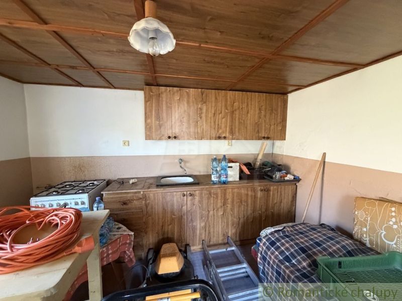 A kitchen in a family house with a wooden ceiling paneling and a gas stove.