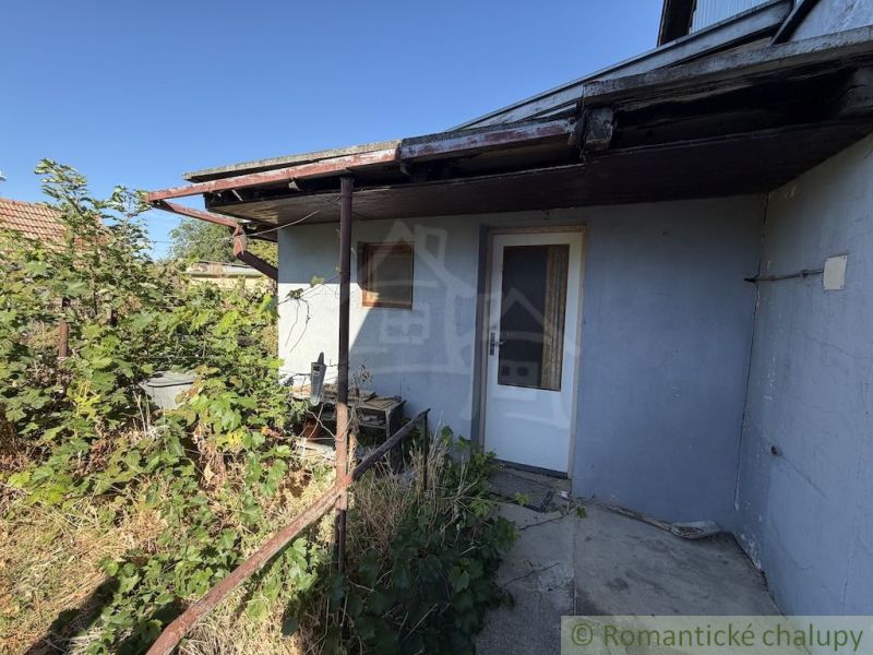 The back part of a family house in Tvrdošovce with a metal roof and greenery.