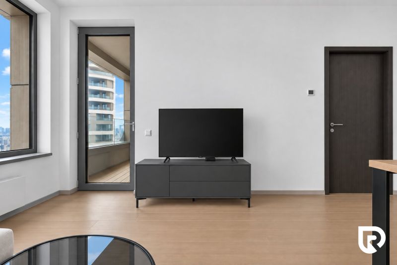 Living room in a two-room apartment with a wooden decor floor and a television.
