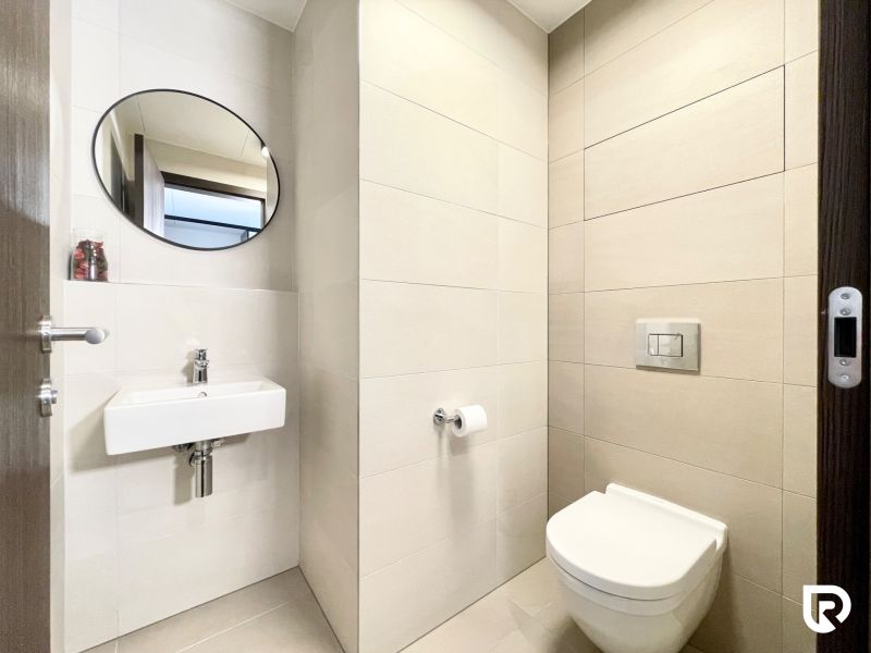 Bathroom in a 2-room apartment with a sink, toilet, and round mirror.