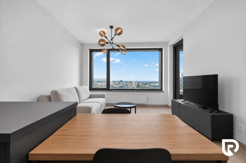 Bright living room with wood-patterned flooring, large window, and modern furniture in a 2-room apartment.