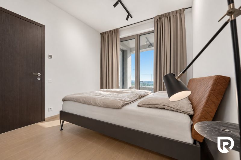 A bedroom with a double bed, a large window, and a wooden decor floor in a two-room apartment.