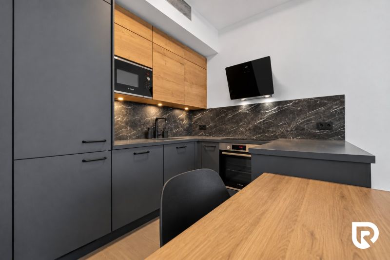 A kitchen unit in a 2-room apartment with a wooden decor floor and modern appliances.
