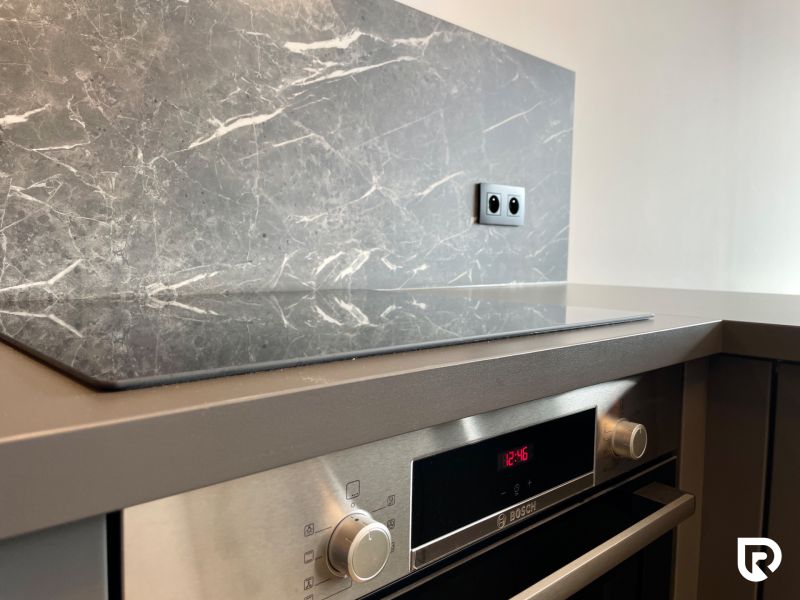 A kitchen unit in a 2-room apartment with an electric oven and marble decor.
