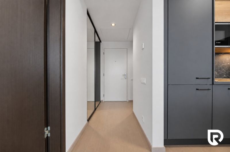 A hallway in a 2-room apartment with a wooden decor floor and white fire door.