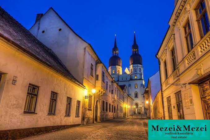 A historic alley in Trnava with a cathedral in the background, ideal for living in a 2-room apartment.