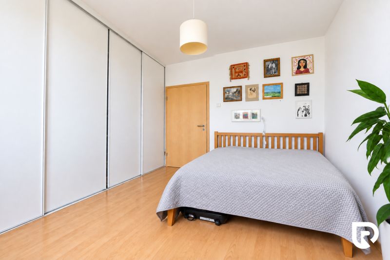 A bedroom with a wooden decor floor and paintings in a three-room apartment.