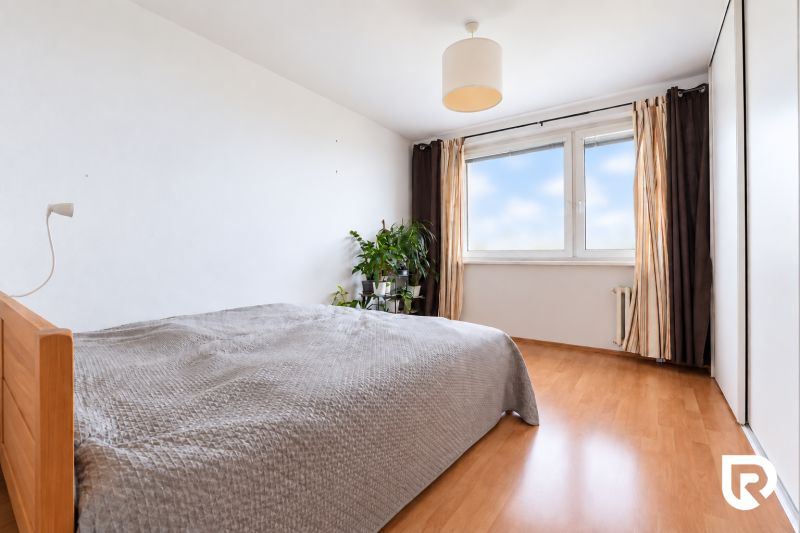 Bedroom in a 3-room apartment with a large window and a wooden decor floor.