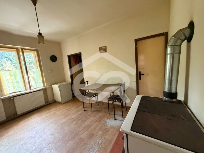 A kitchen in a family house with a wooden decor floor, a table, and a stove.